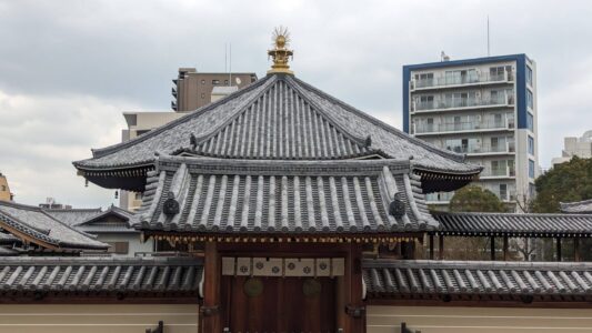 Image d'un temple traditionnel dans le quartier coréen d'Osaka, avec une architecture typique et des détails colorés, entouré de verdure